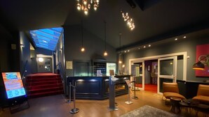 Un moderno vestíbulo de hotel con mostrador de recepción, una escalera y una zona de bar.