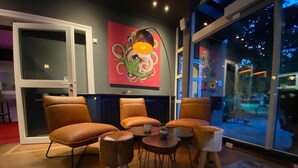Una sala de estar moderna con sillones de cuero, una mesita redonda y un cuadro abstracto llamativo en la pared.