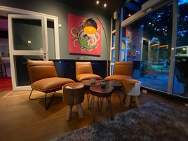 Una sala de estar moderna con sillones de cuero, una mesita redonda y un cuadro abstracto llamativo en la pared.
