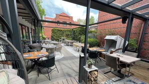 Un patio al aire libre con varias mesas y sillas, una parrilla y una terraza de madera.