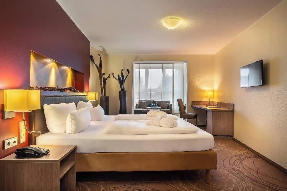Une chambre d’hôtel équipée d’un lit, d’une table de chevet, d’une lampe, d’une télévision et offrant une vue sur l’extérieur.
