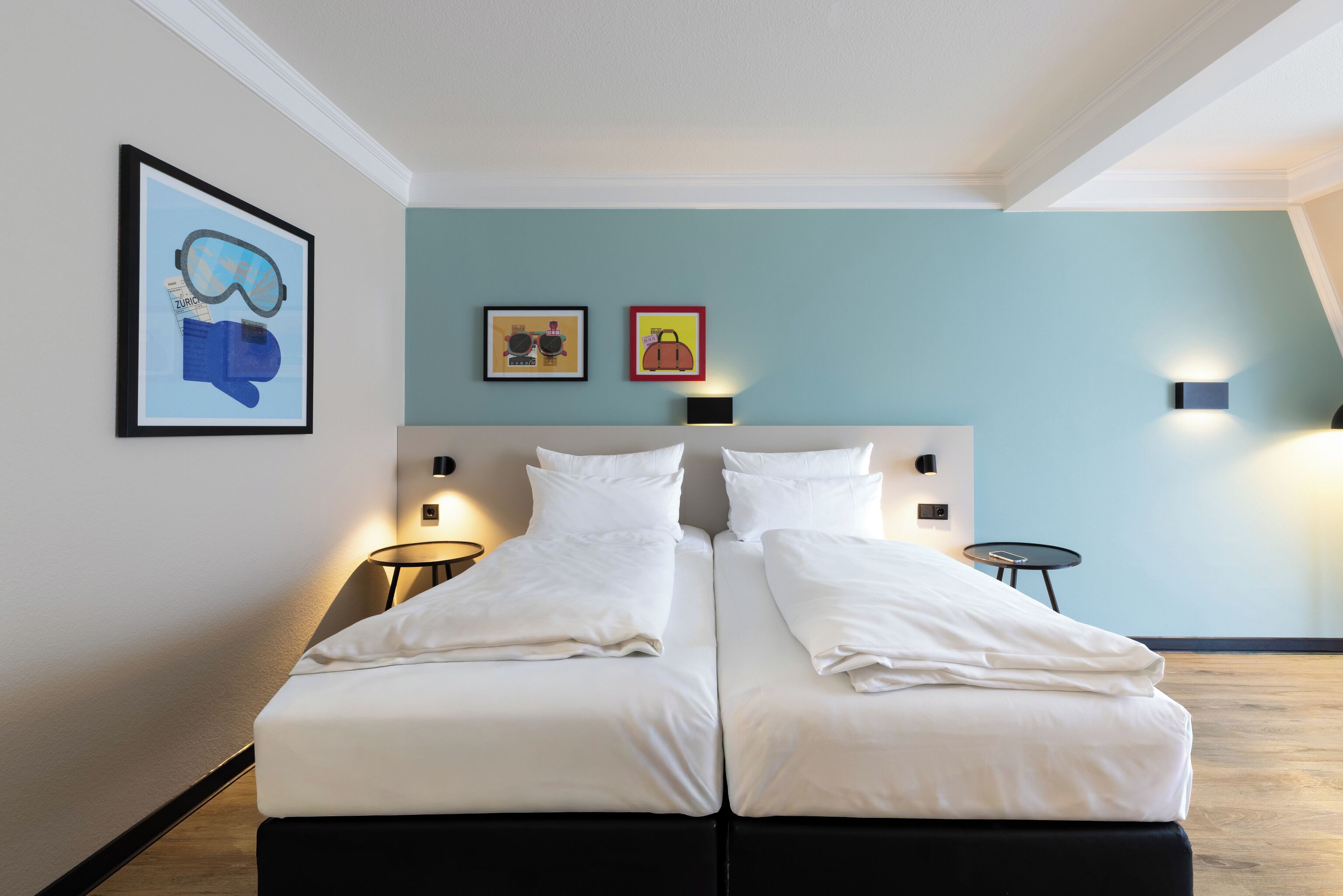 Una cama doble con ropa de cama blanca, dos mesitas de noche y lámparas de pared.