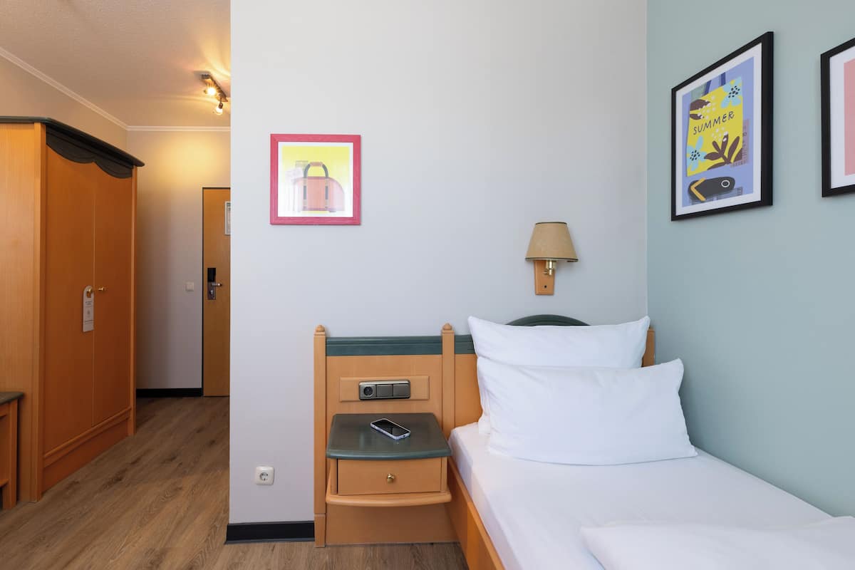Une chambre d’hôtel avec un lit, une table de chevet, une lampe et un tableau encadré au mur.