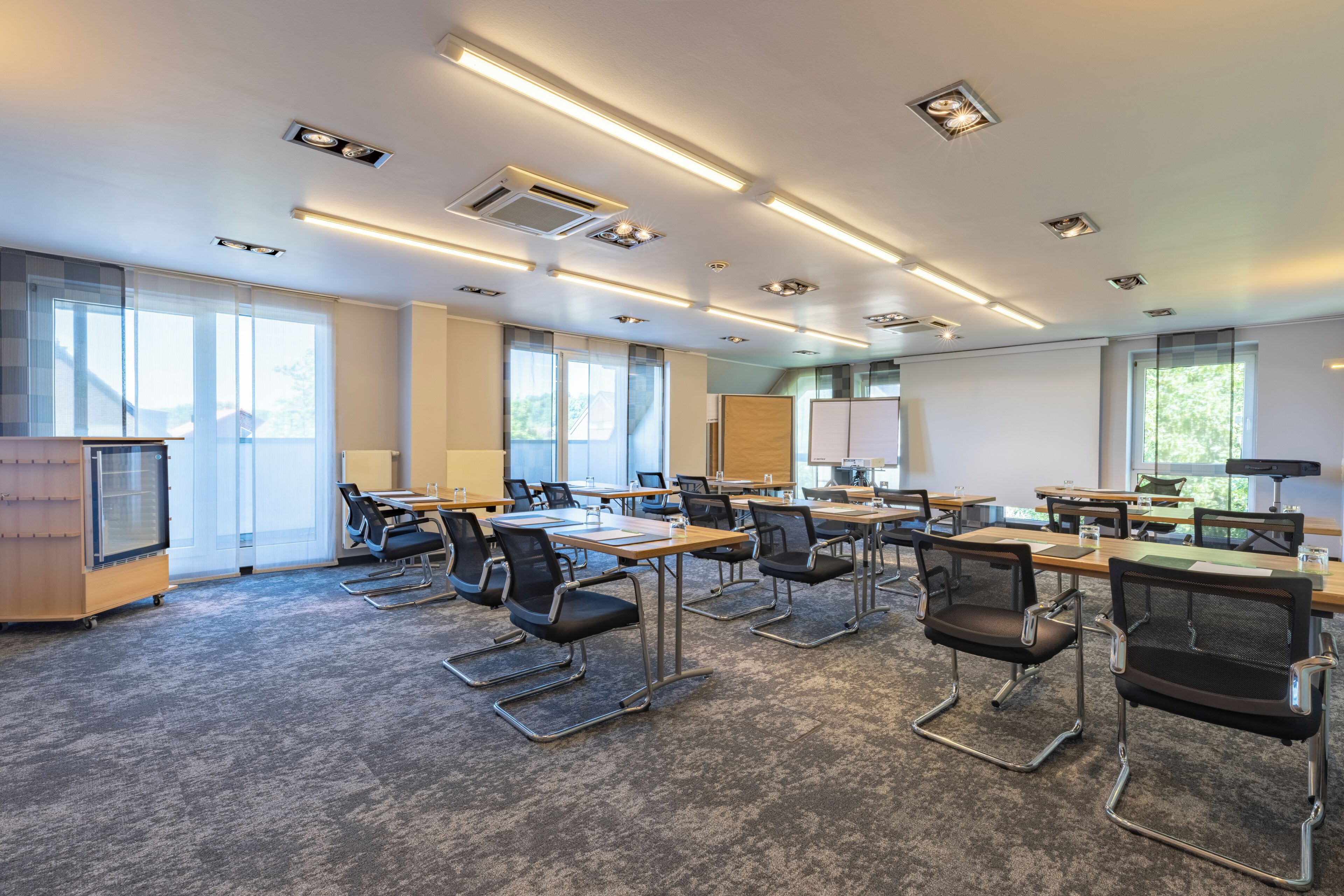 A conference room with tables, chairs, and a projector screen.