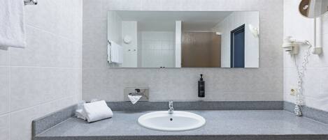 A bathroom with a white sink, a mirror, a towel rack, and a hairdryer.