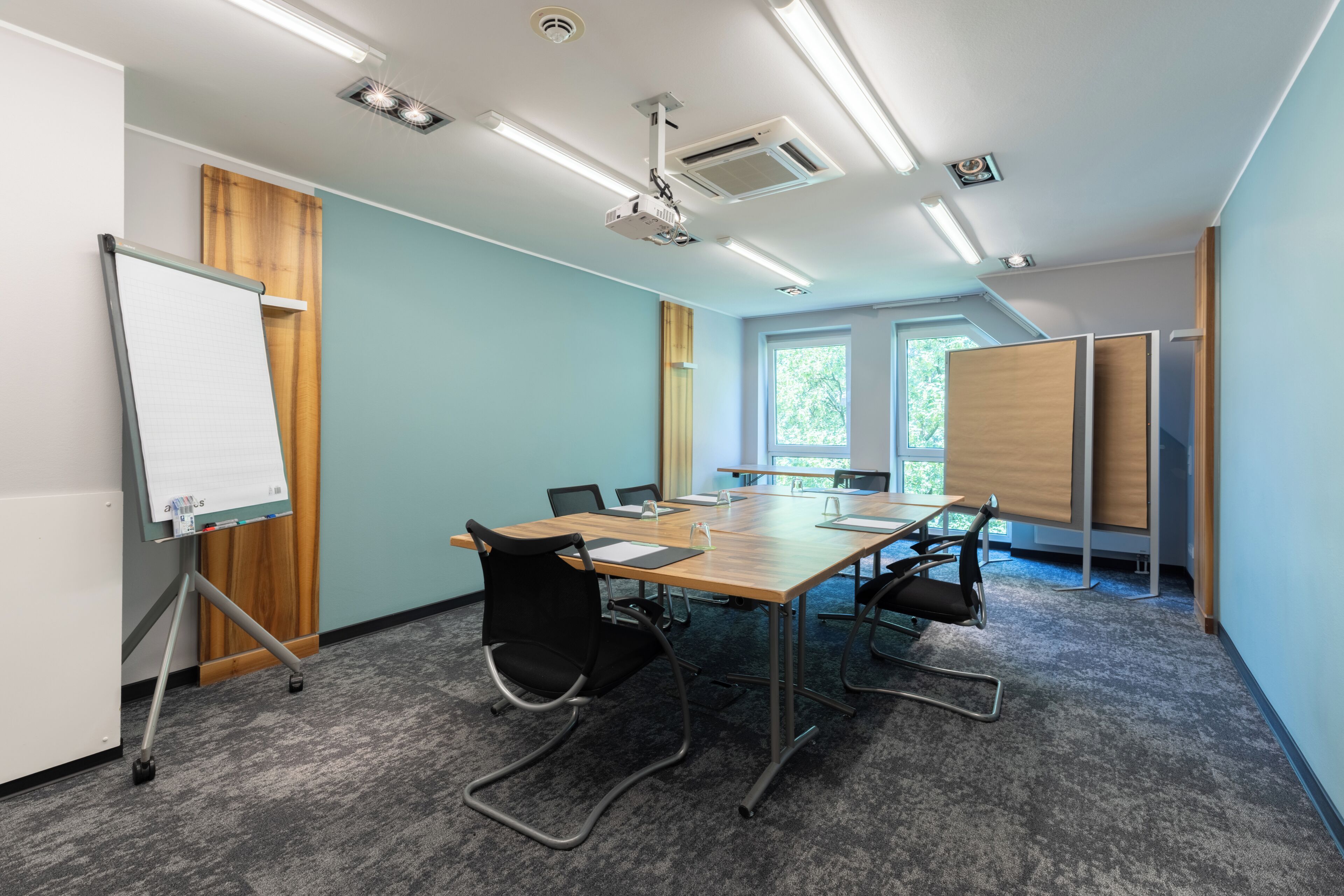 A conference room with a long table, chairs, a whiteboard, and a projector.