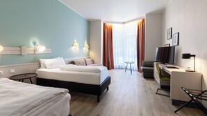 Una habitación de hotel con una cama, un escritorio, un televisor y una mesita.