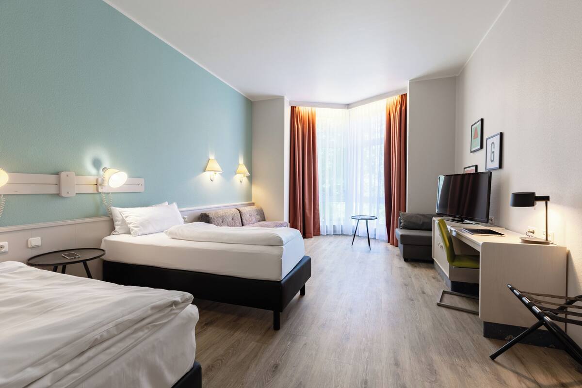 Une chambre d’hôtel avec un lit, un bureau, une télévision et une petite table.