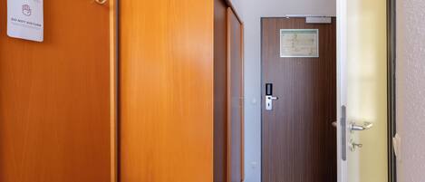 Ein Hotelkorridor mit Holzwänden, einem Kleiderständer, einer Tür mit einem Schild und einer Bank.