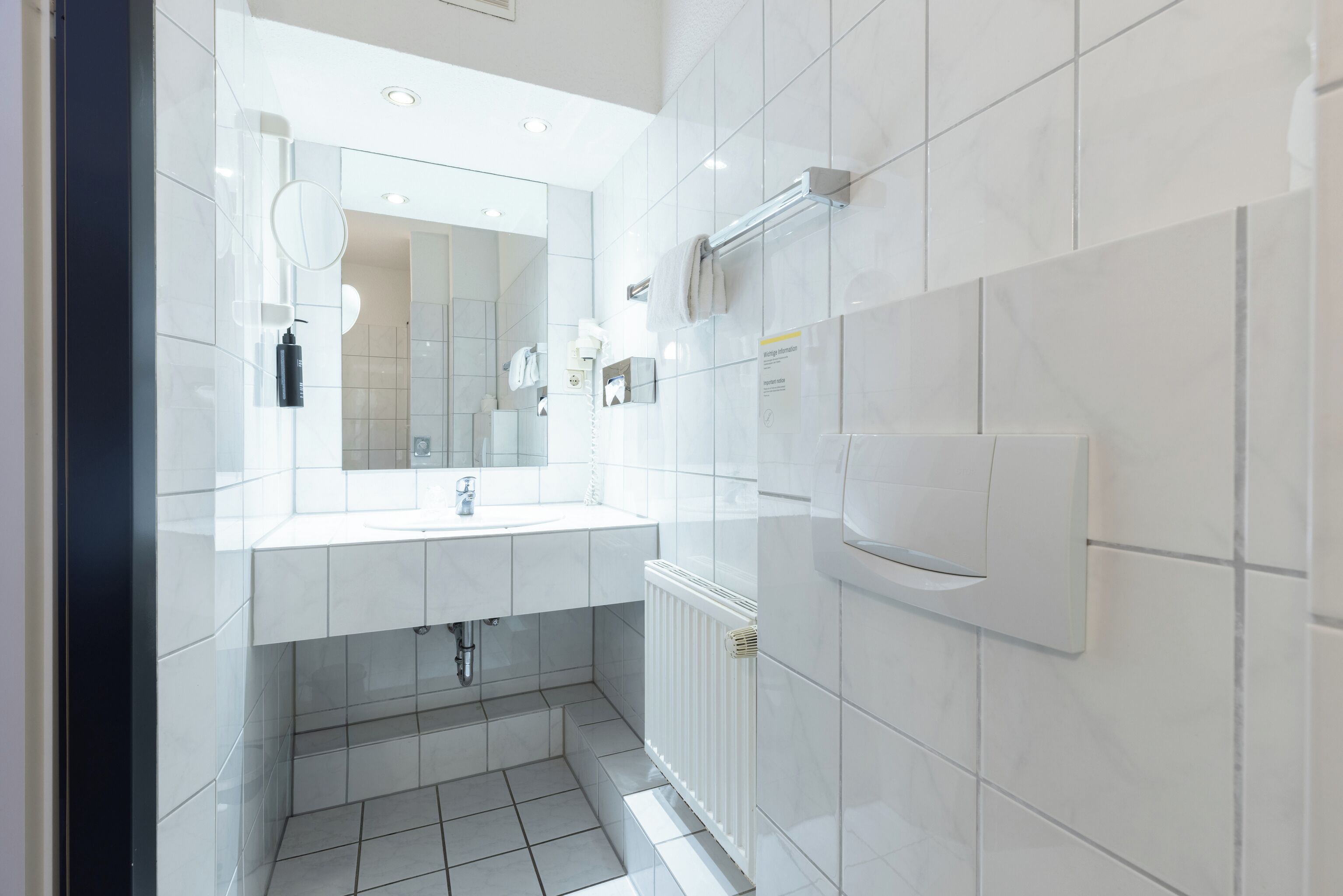 Une salle de bain moderne avec un lavabo blanc, un miroir et un porte-serviettes.