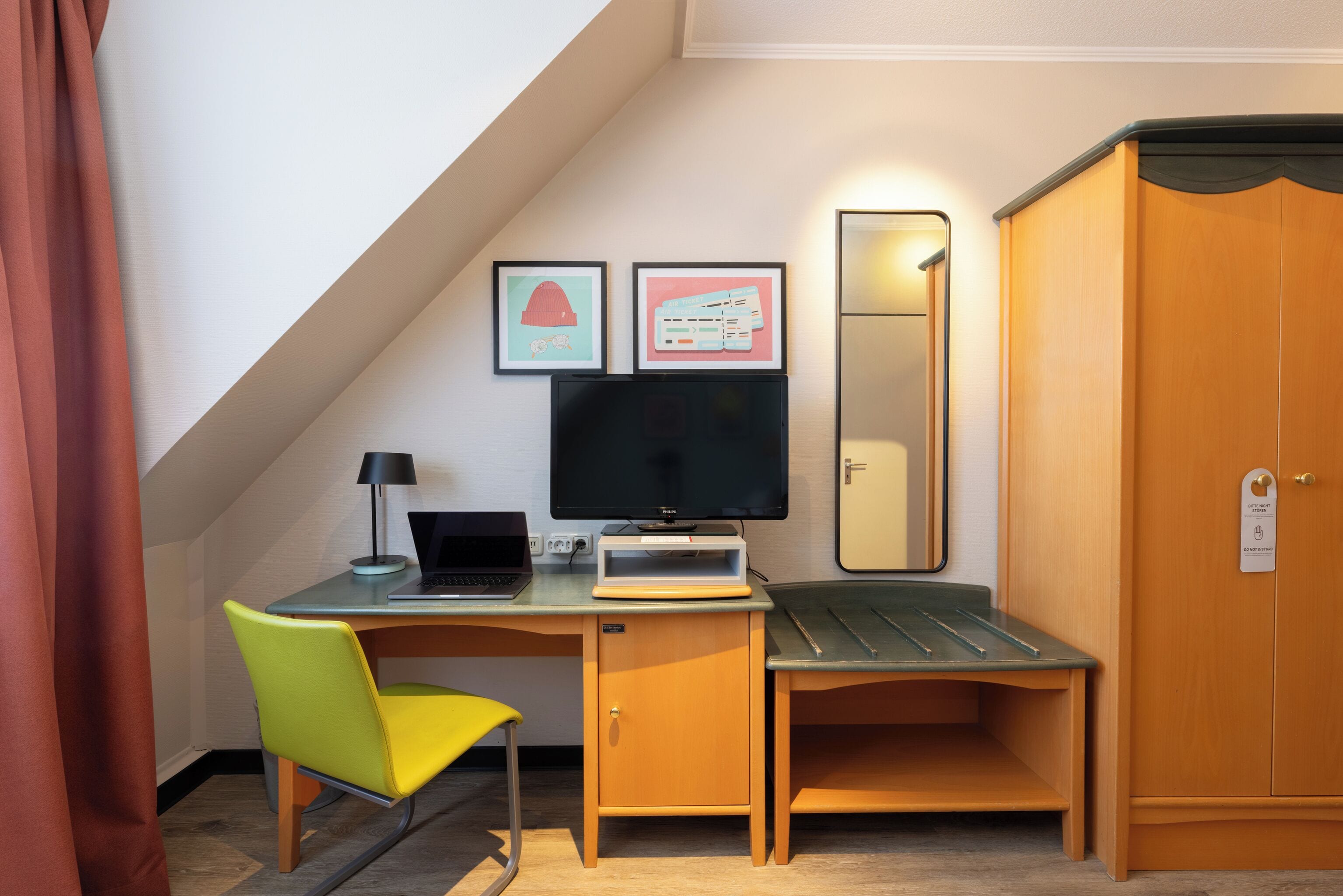 Quarto compacto com escrivaninha, cadeira, computador e guarda-roupa.