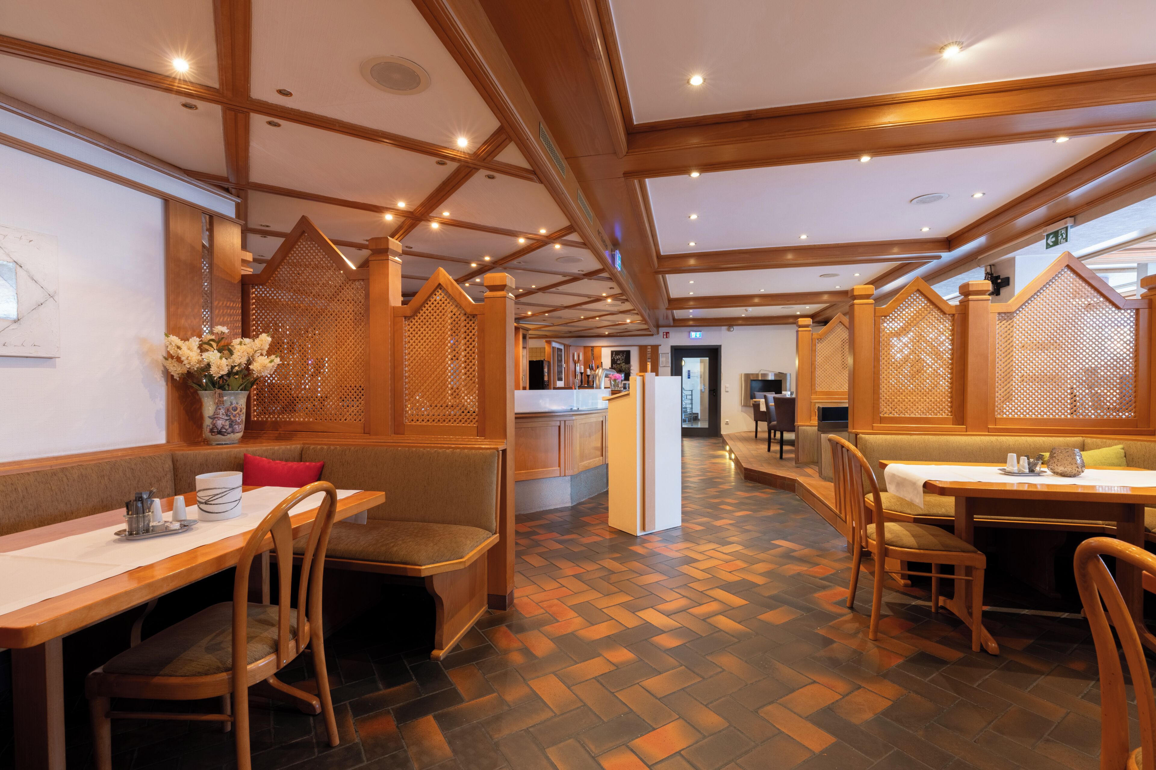 A restaurant with wooden furniture, a herringbone floor pattern, and a central island.