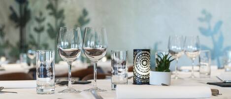 A dining table set with multiple wine glasses, a small potted plant, and a decorative item.