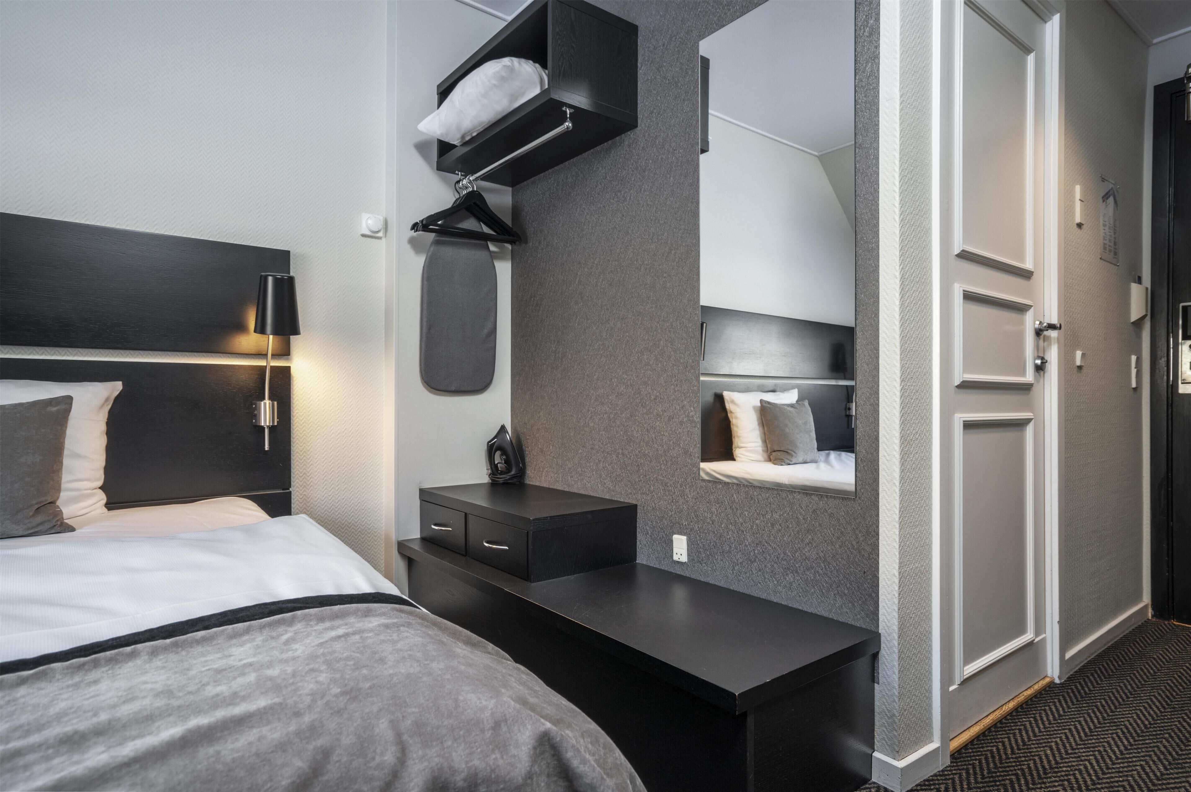 Una habitación de hotel moderna con cama, mesita de noche y armario empotrado.