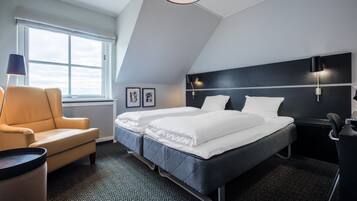 A modern hotel room with a large bed, a chair, and a desk.