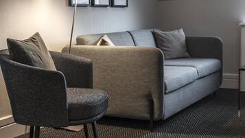 Una sala de estar moderna con un sofá gris, un sillón oscuro y una alfombra estampada.