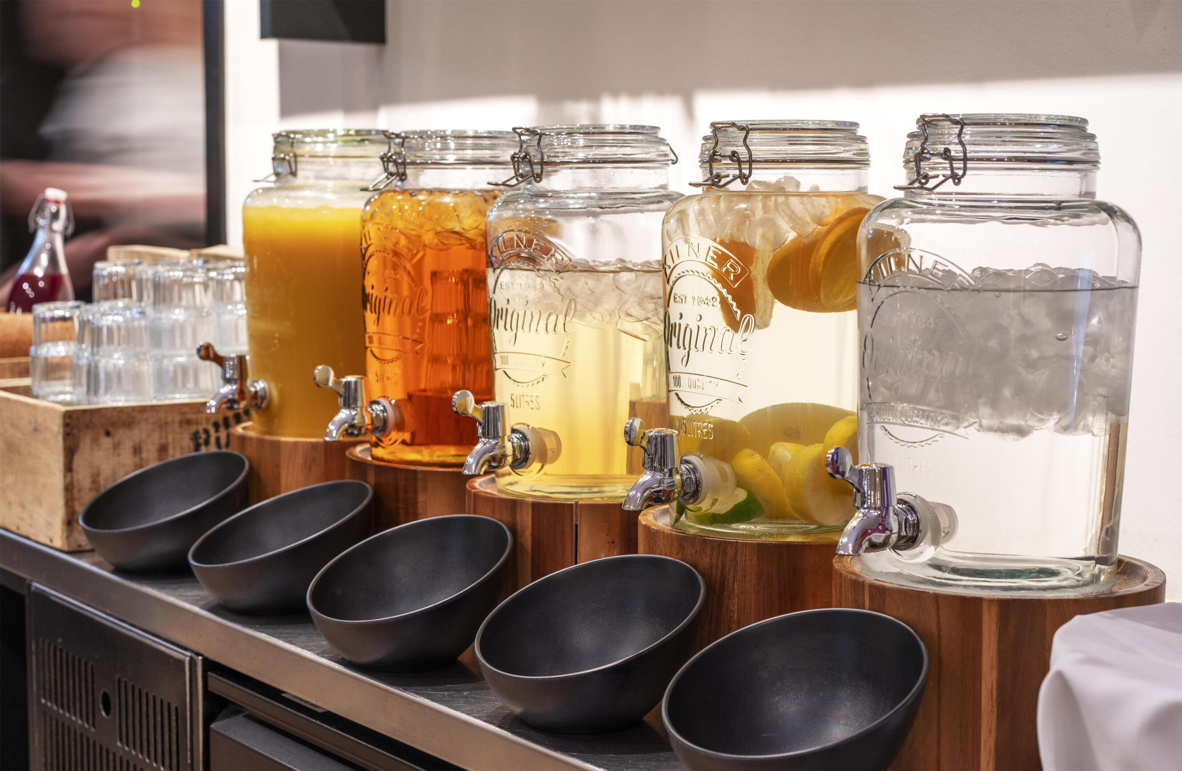A beverage station with multiple taps and glass containers.