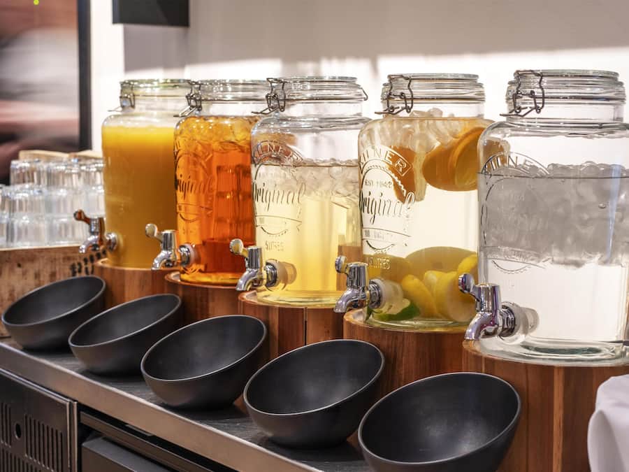 A beverage station with multiple taps and glass containers.