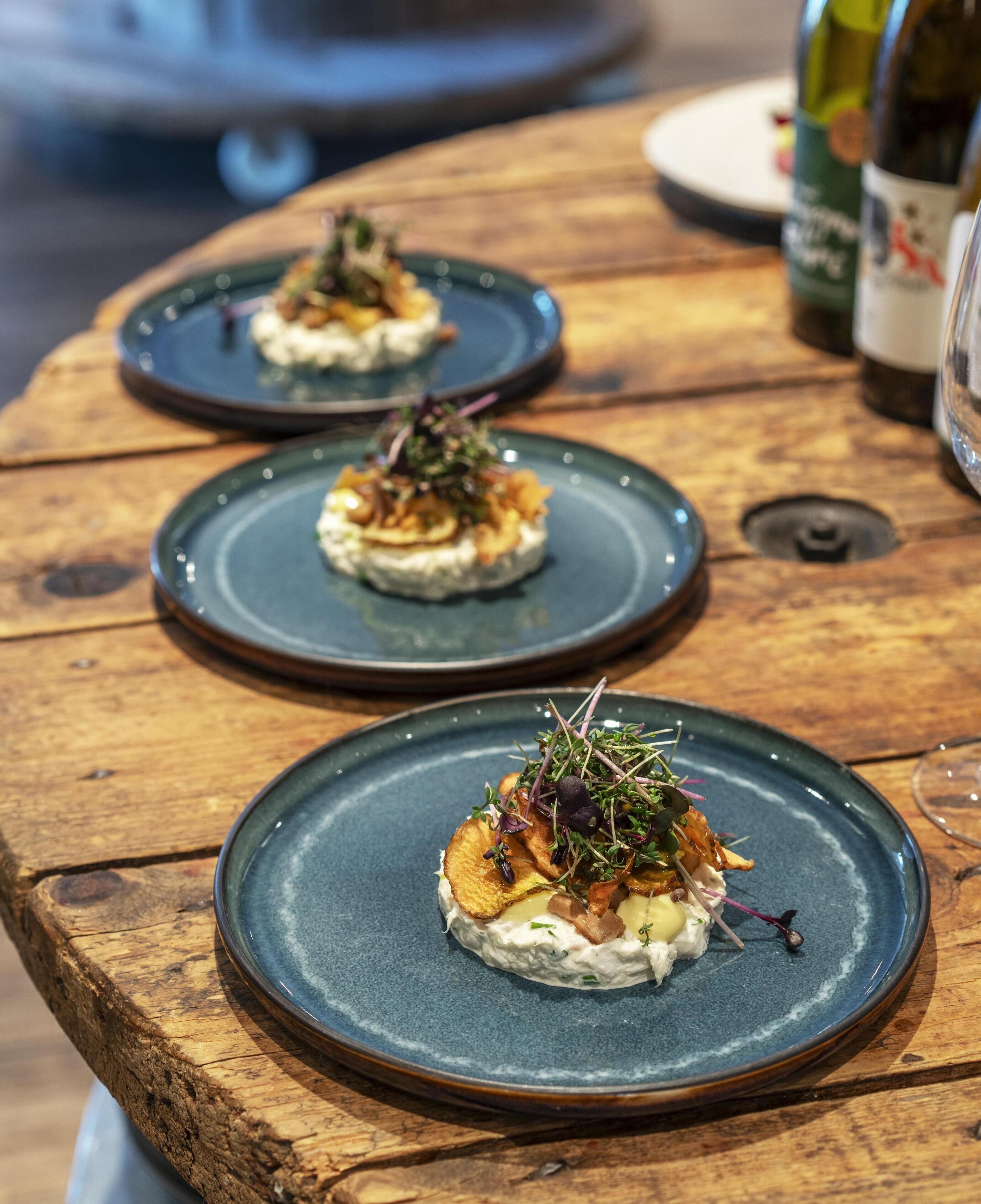 A wooden table with three plates of food.