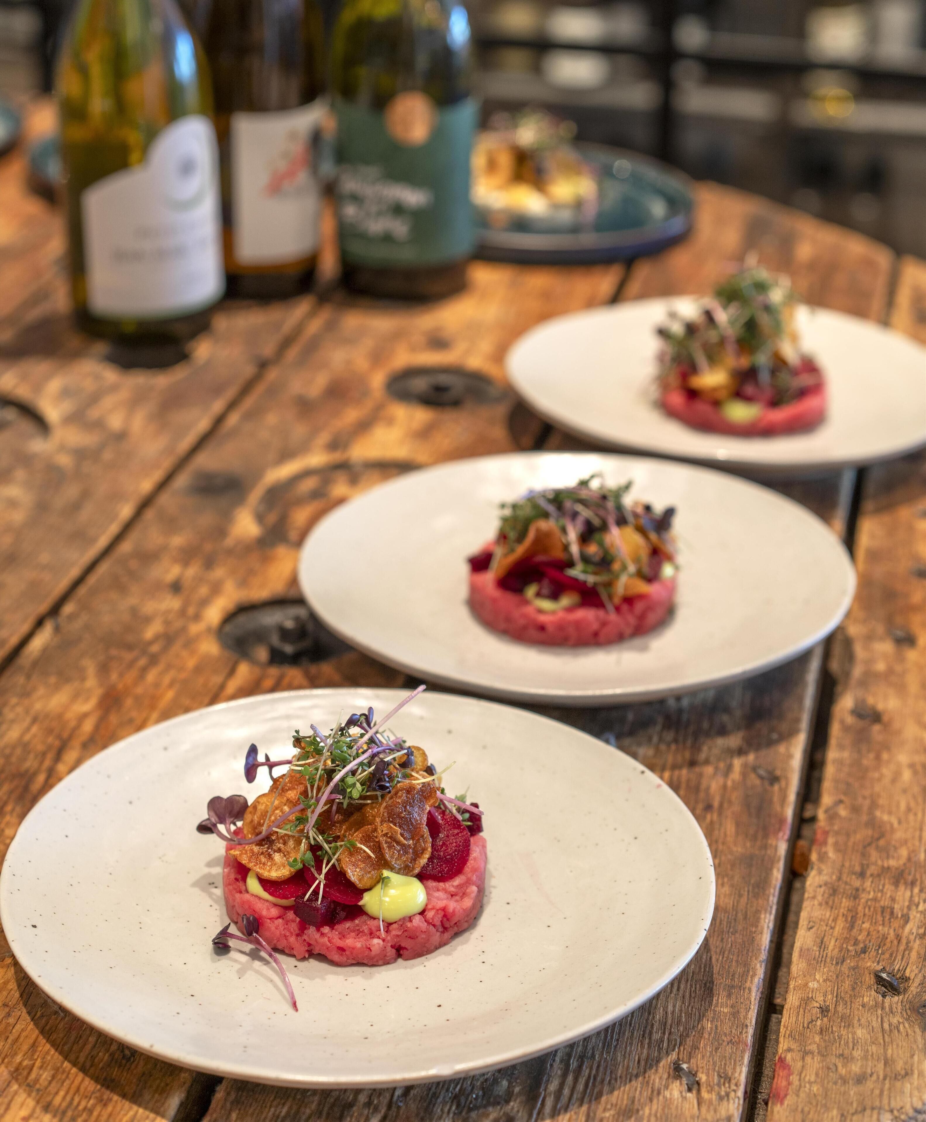 A wooden table with three plates of food.