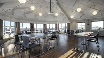 Una amplia sala de conferencias con techos altos, ventanas grandes y mobiliario moderno.