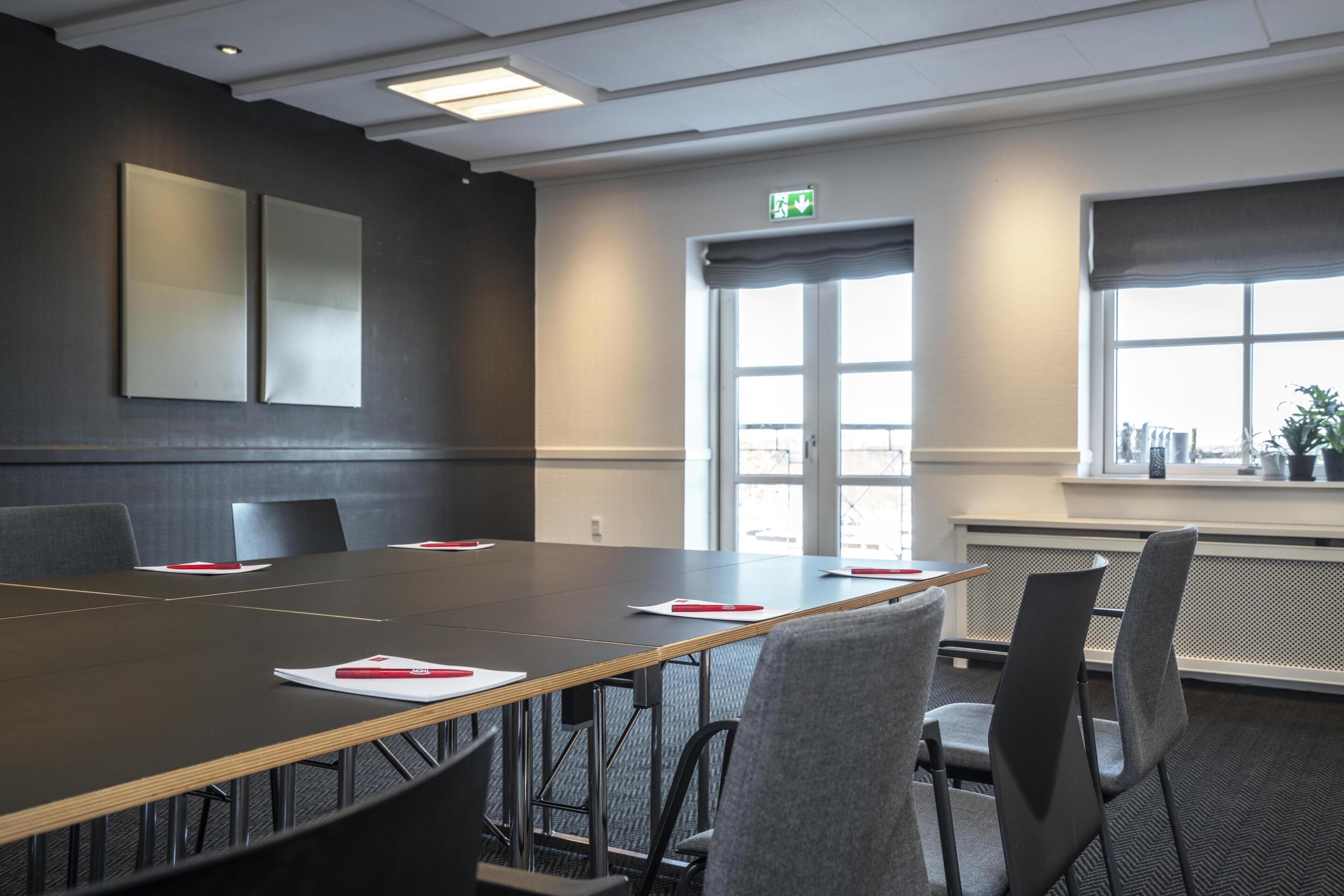 A conference room with a long table, chairs, and a large window.