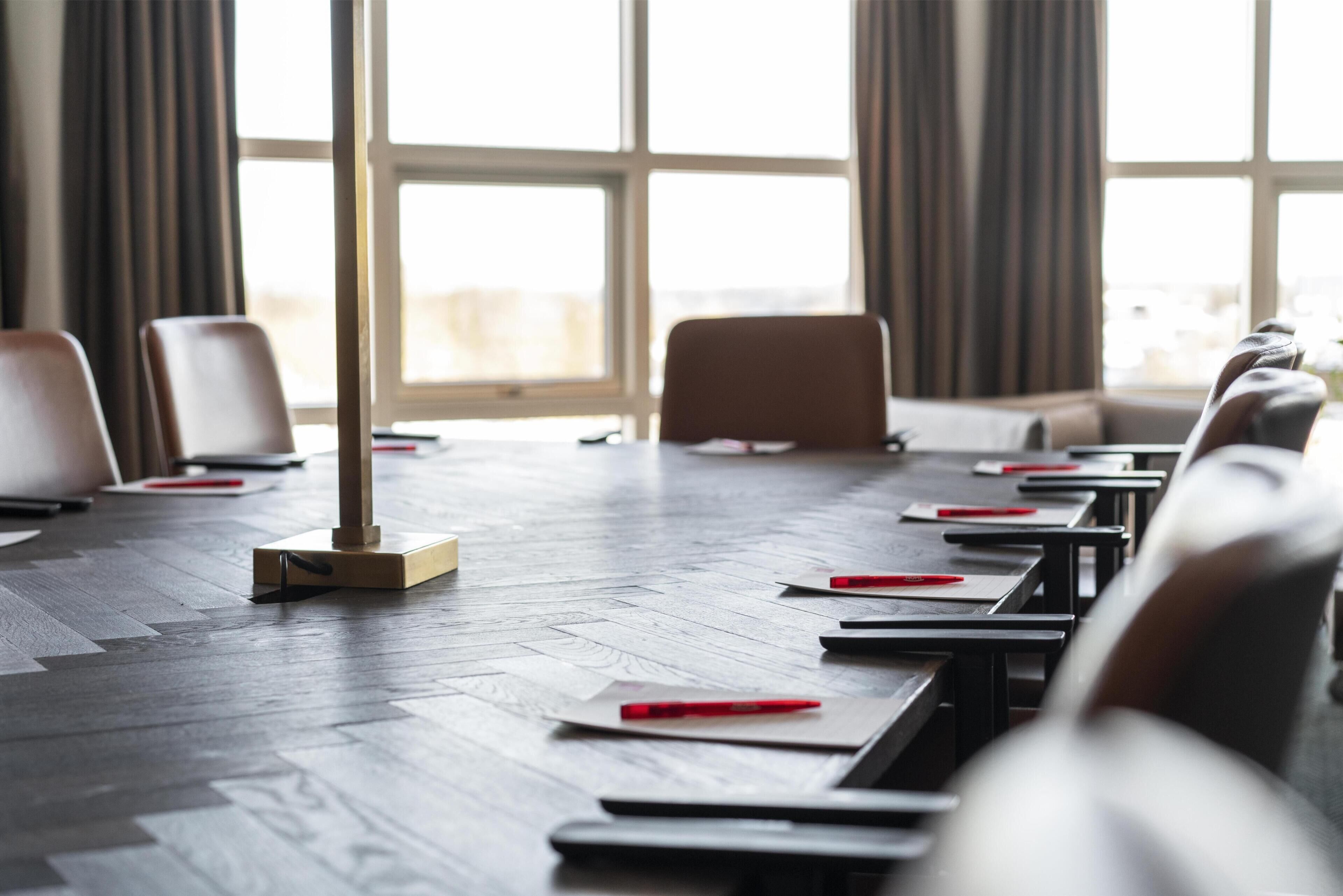 Un salón de conferencias con una larga mesa, sillas y un atril.