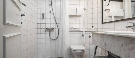 A bathroom with a black and white checkered floor, a white toilet, a shower with a curtain, and a sink with a mirror above it.