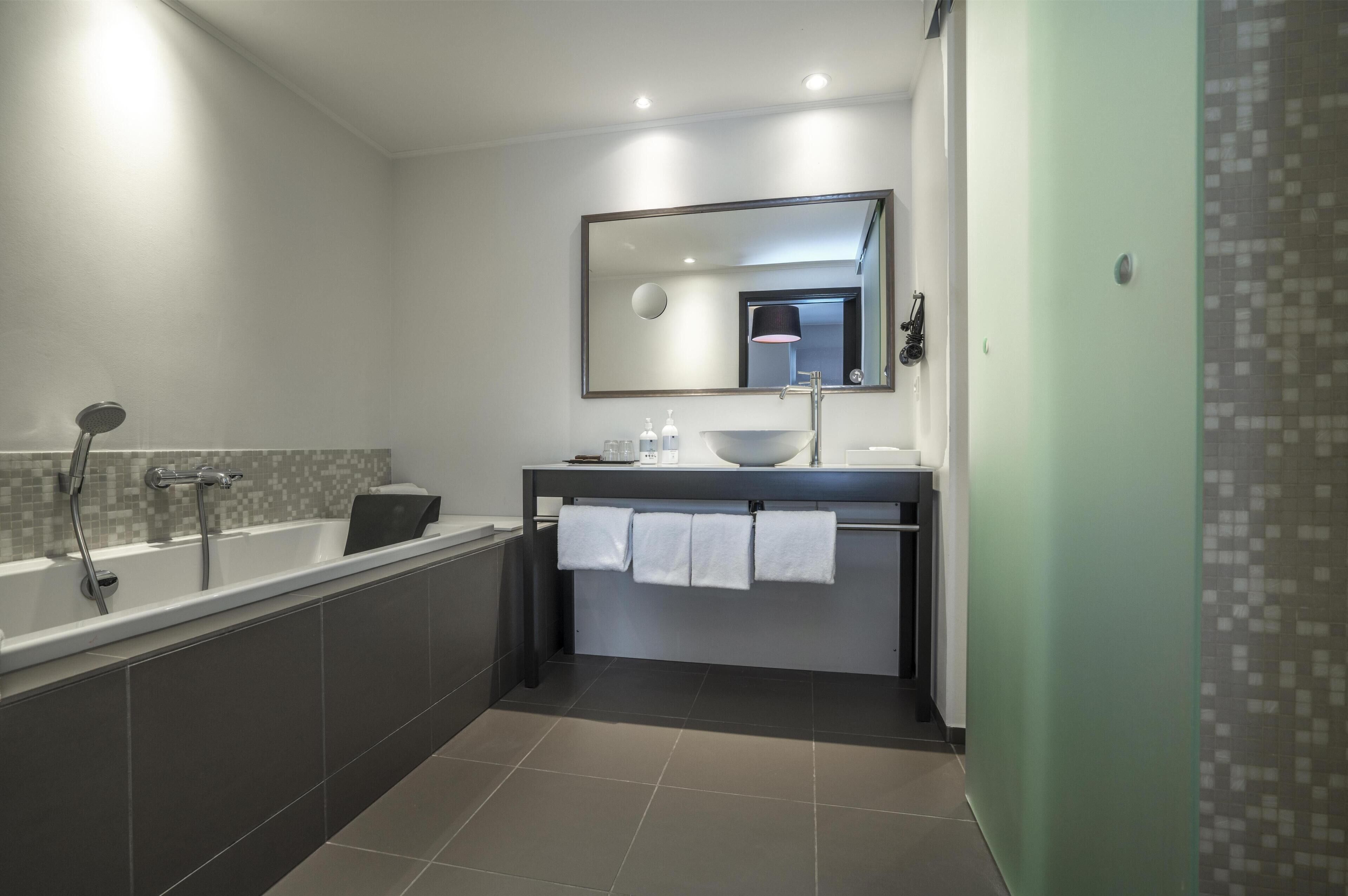 A modern bathroom with a bathtub, a sink, and a mirror.