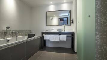 Un bagno moderno con una vasca, un lavandino e uno specchio.