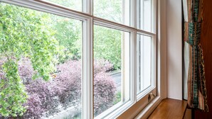 A room with a large window offering a view of trees and a road. - Nayland Hotel (London)
