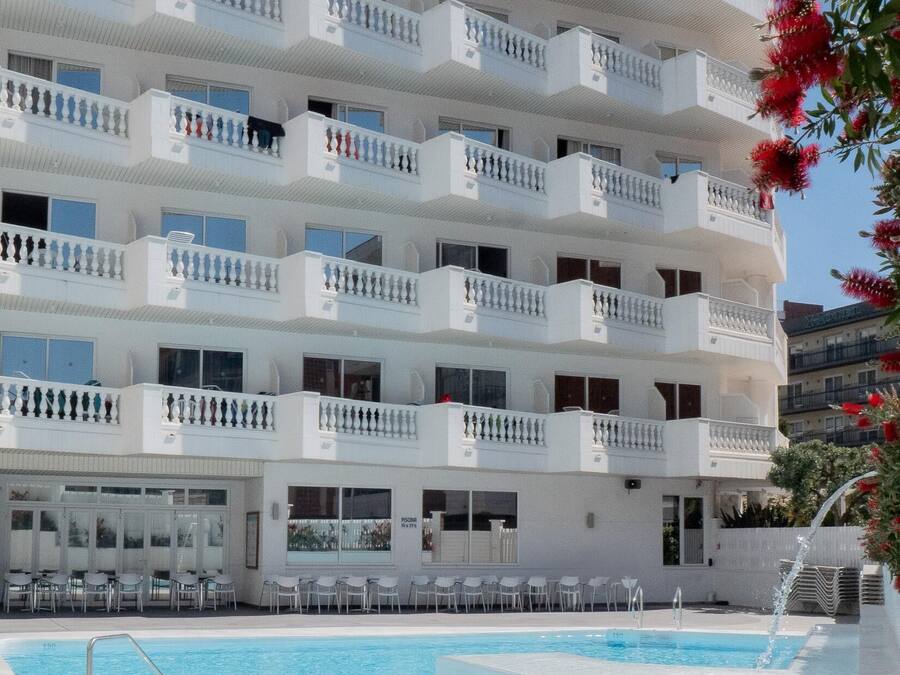 Ett hotell med flera våningar, balkonger, en swimmingpool och utomhusplats med sittmöbler.