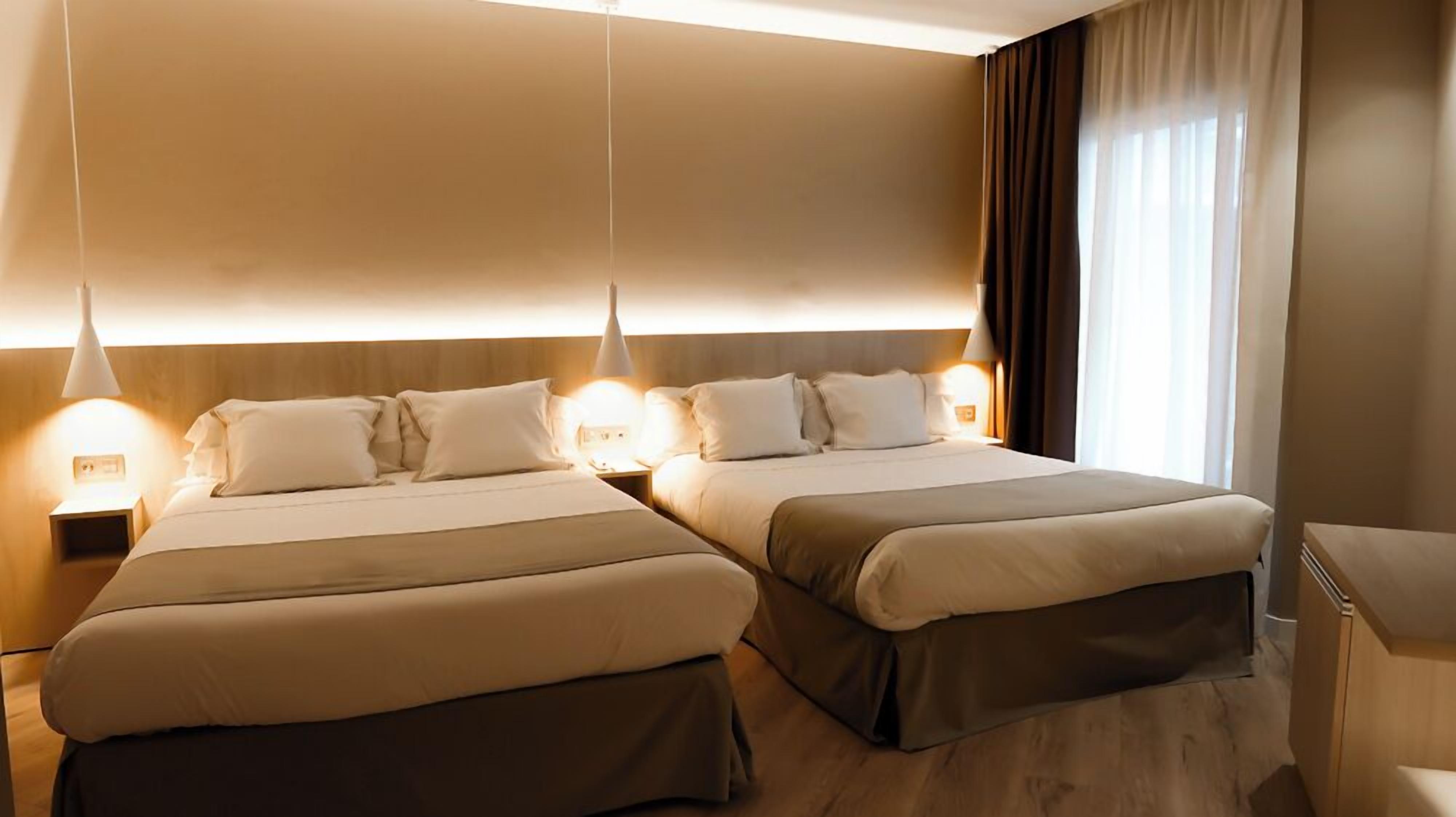 Une chambre d’hôtel avec deux lits, une table de chevet et un bureau.