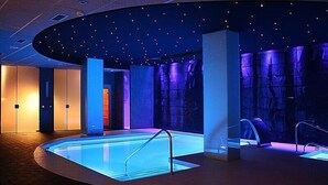 Una piscina interior de diseño moderno, rodeada de paredes con una textura e iluminación únicas.