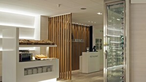 Un interior de restaurante moderno con un separador de madera, una vitrina de vidrio y una barra con una máquina de café.