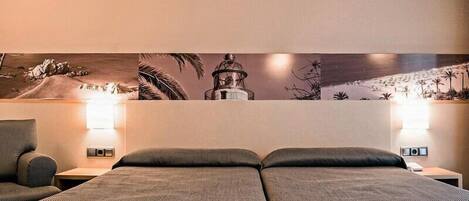 A hotel room with two beds, nightstands, wall art, and a lamp.
