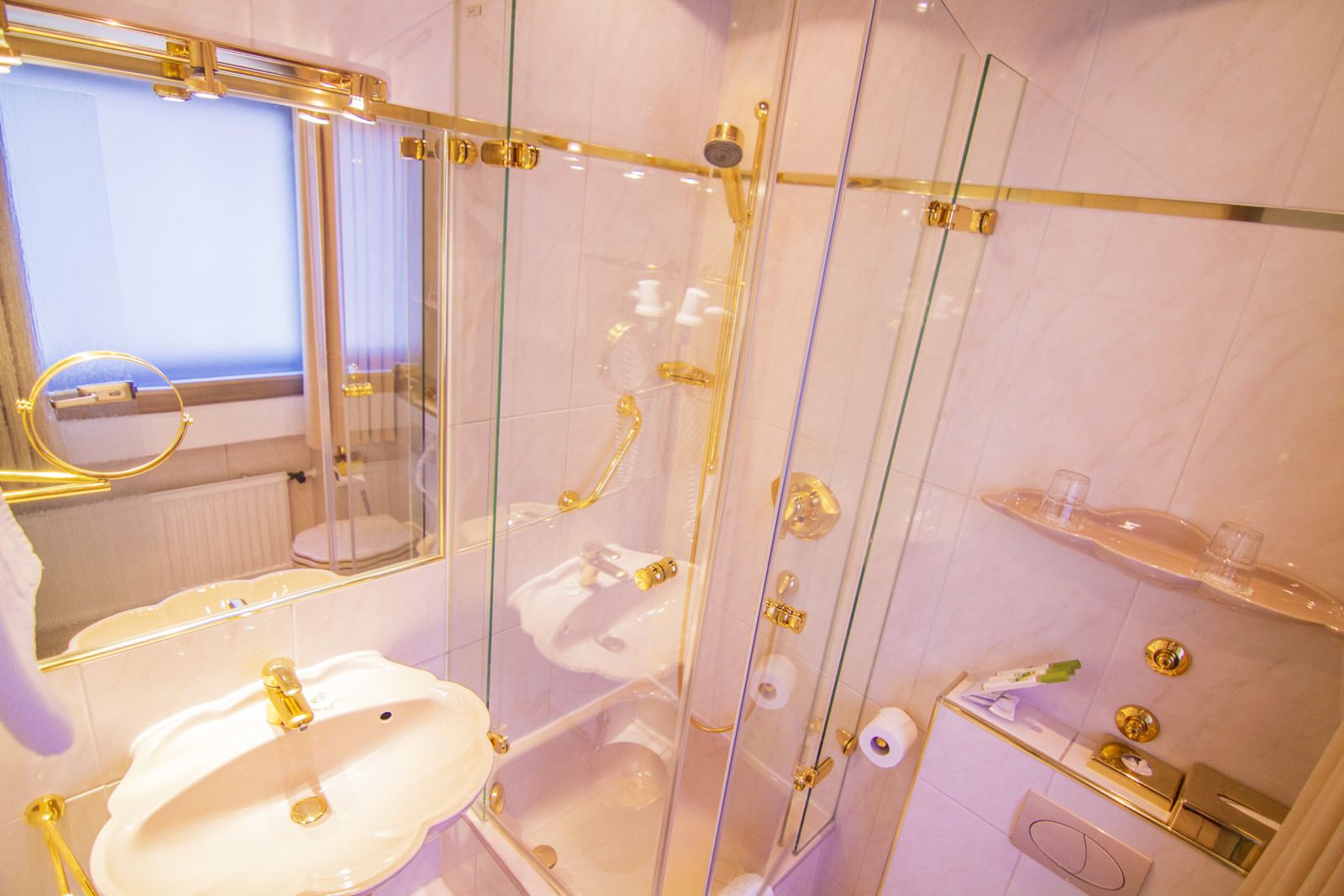 A bathroom with a glass-enclosed shower, a white sink, and a mirror.