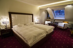 A hotel room with a large bed, two bedside tables with lamps, a desk with a chair, and a window with a view.
