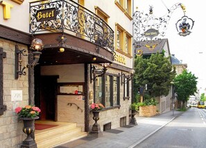 A hotel with a balcony, a sign reading "Hotel", and a street view with a tram in the background. - Zur Weinsteige (Stuttgart)