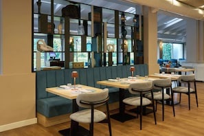 A restaurant with booths and tables, a wooden floor, and a view of the outdoors. - Four Points Flex by Sheraton Parma (Parma)