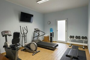 A gym with a treadmill, elliptical, stationary bike, and free weights. - Four Points Flex by Sheraton Parma (Parma)