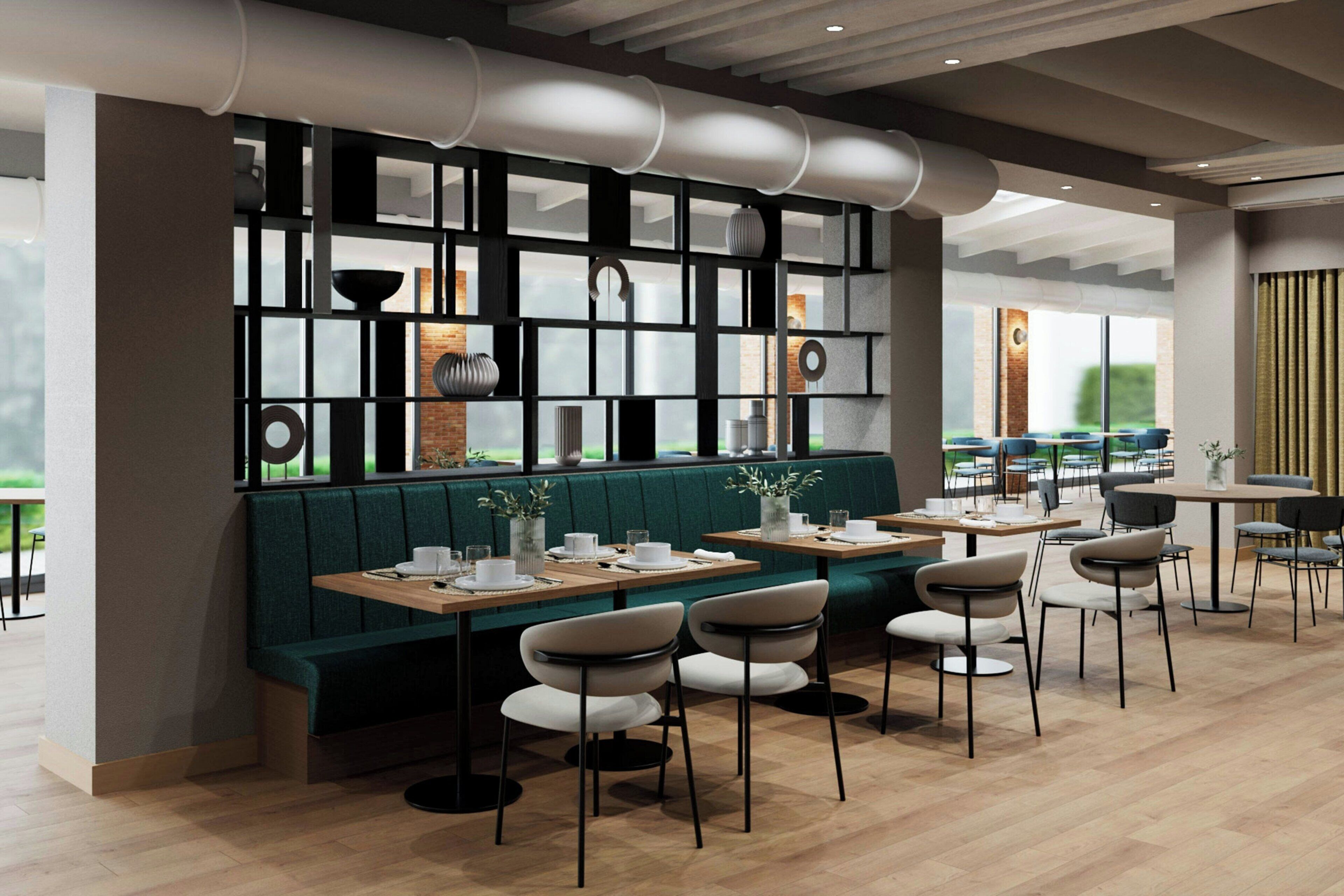 A modern restaurant with a green booth seating area, wooden tables, and chairs.