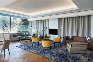 Un salon moderne comprenant un canapé, des fauteuils, une table basse et un téléviseur.
