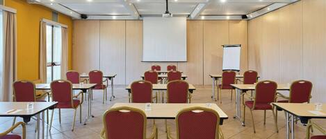 A conference room with tables and chairs, a projector screen, and a whiteboard.