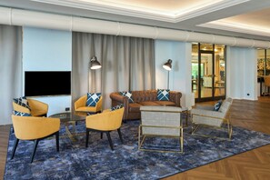 A modern living room with a flat-screen TV, two armchairs, a sofa, and a coffee table. - Four Points Flex by Sheraton Parma (Parma)