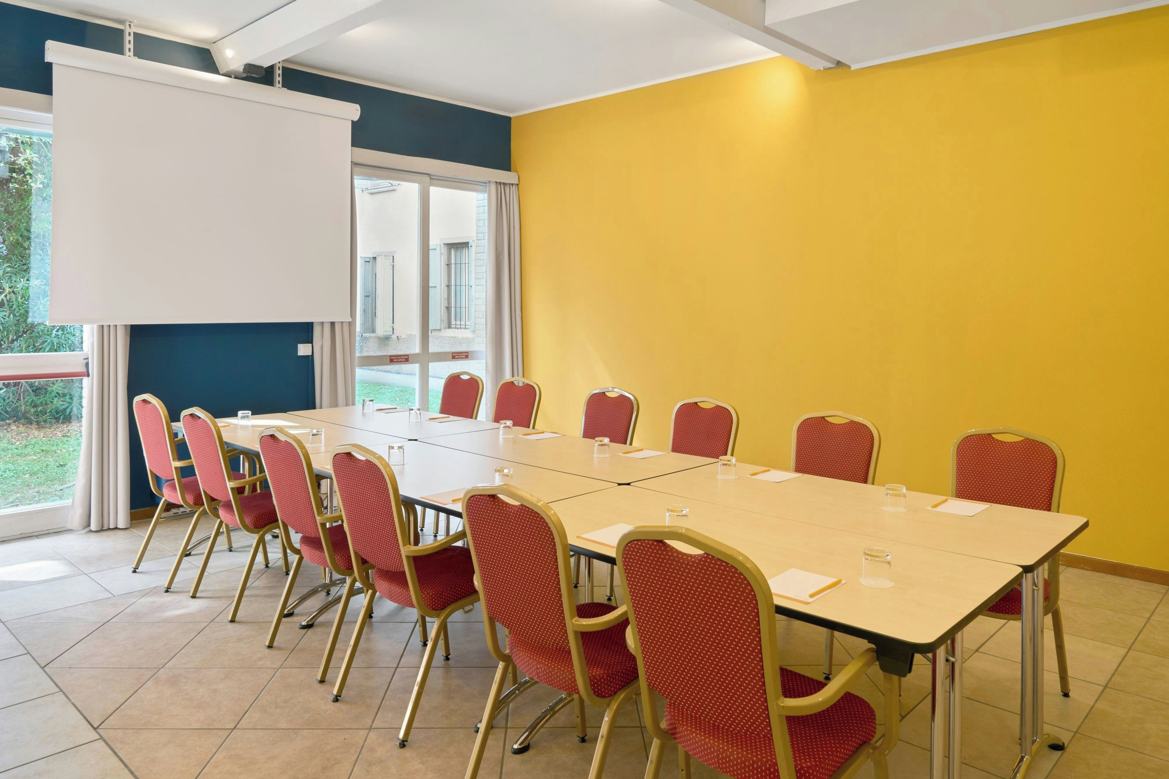 A conference room with a large table, red chairs, and a whiteboard.