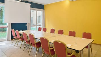 A conference room with a large table, red chairs, and a whiteboard.