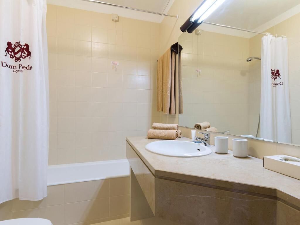 A bathroom with a bathtub, a sink, a mirror, and a towel rack.