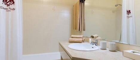 A bathroom with a bathtub, a sink, a mirror, and a towel rack.