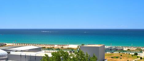 Ein Hotel an der Küste mit Blick auf das Meer, einen Strand und einen Parkplatz.